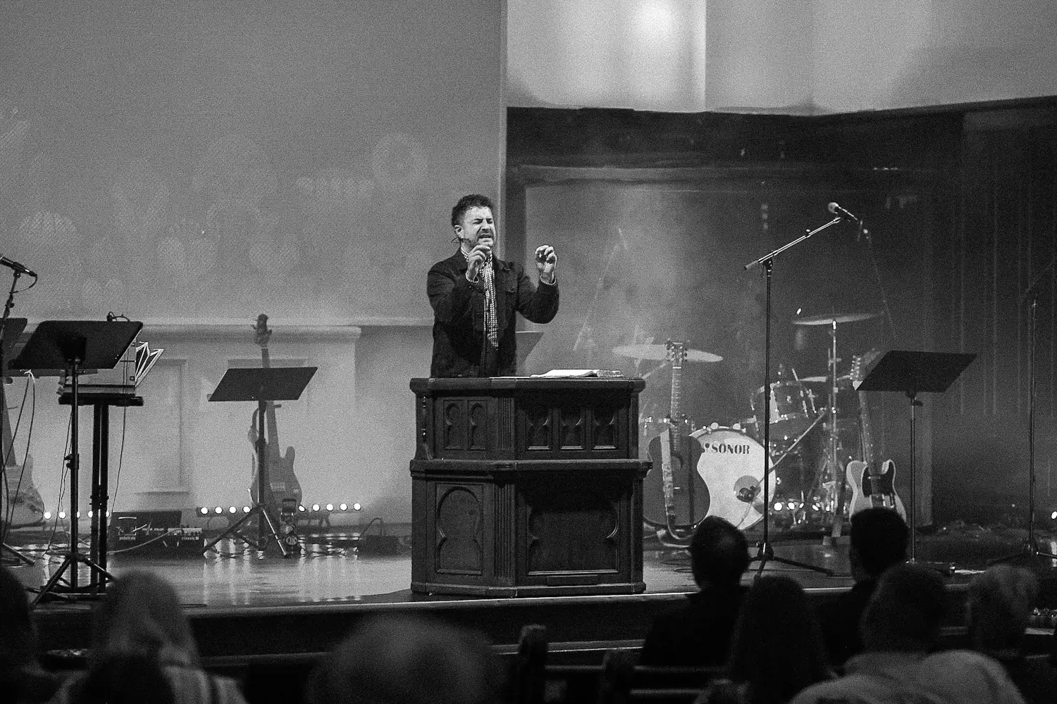 Bubba Jennings preaching from a dark wooden pulpit, in black and white